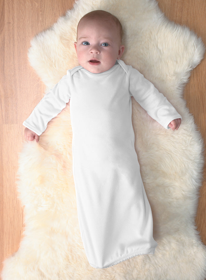 Baby in a white 100% cotton long-sleeved layette lying on a fluffy white rug.