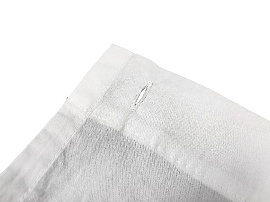 Close up of button hole on white cotton shower curtain, on a white background.