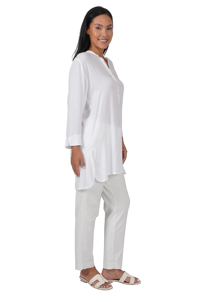 Side view of woman wearing a white rayon tunic with 3 buttons, long sleeves, and a loose fit on a white background.