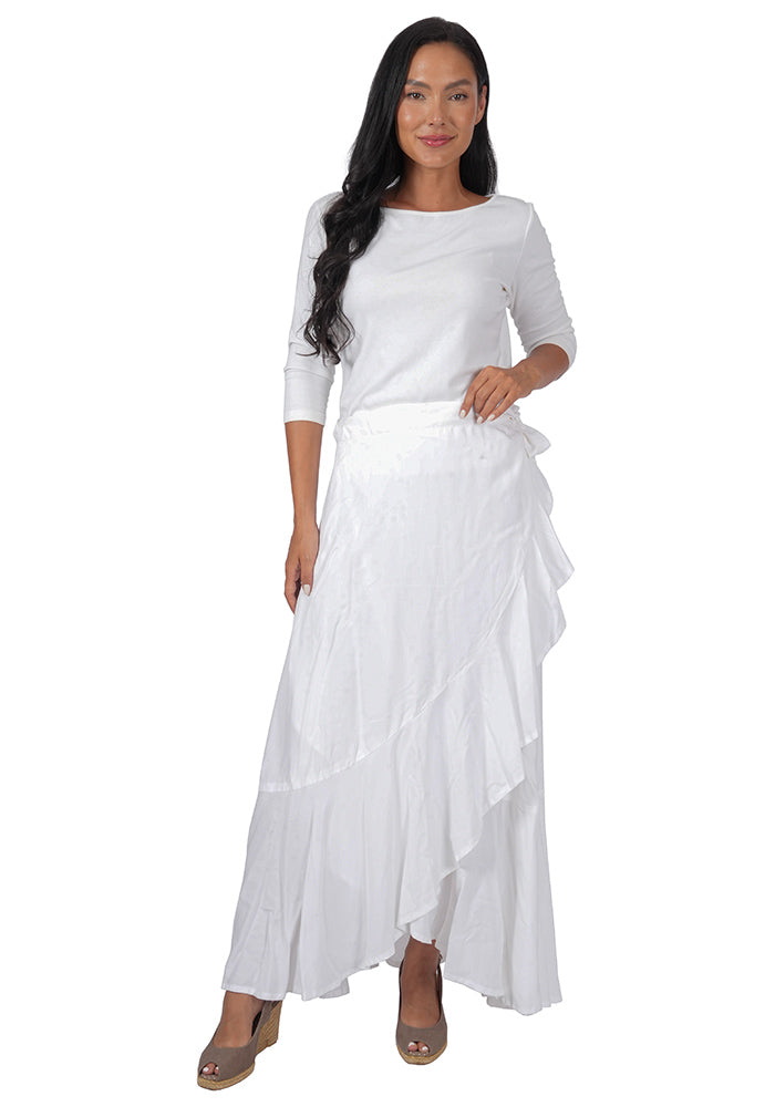 Woman wearing a white top with an ankle length, side-tied, flowing white skirt on a white background.