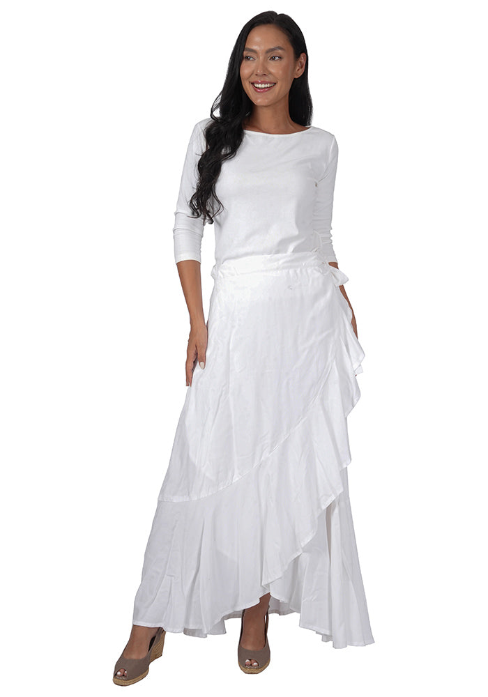 Woman wearing a white top with an ankle length, side-tied, flowing white skirt on a white background.