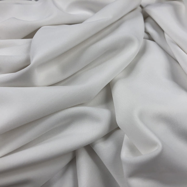 Close-up of white fabric in folded layers to show weight and texture.