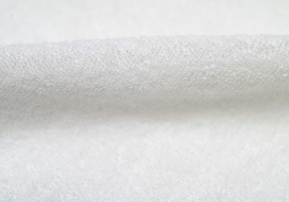 Close-up of folded white terry cloth fabric loop texture.