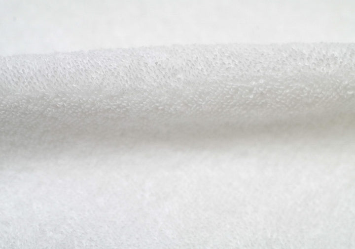 Close-up of folded white terry cloth fabric loop texture.