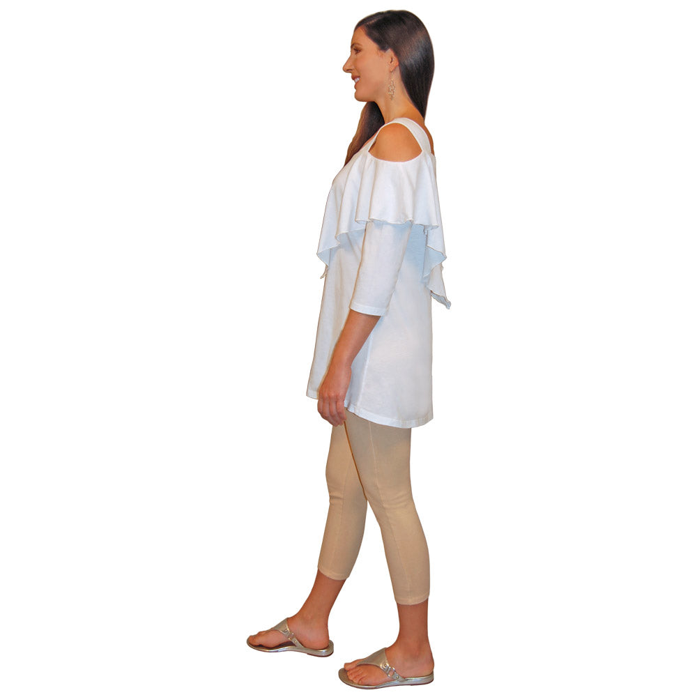 Side view of a woman wearing a white, 3/4 sleeve, flowy top with shoulder cutouts and hem that ends at the top of the thigh, and beige capri pants on a white background.