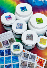 Full-color Ice Dye sticker sheets placed on  lids for corresponding dye containers from Dharma Trading Co. on a rainbow background.