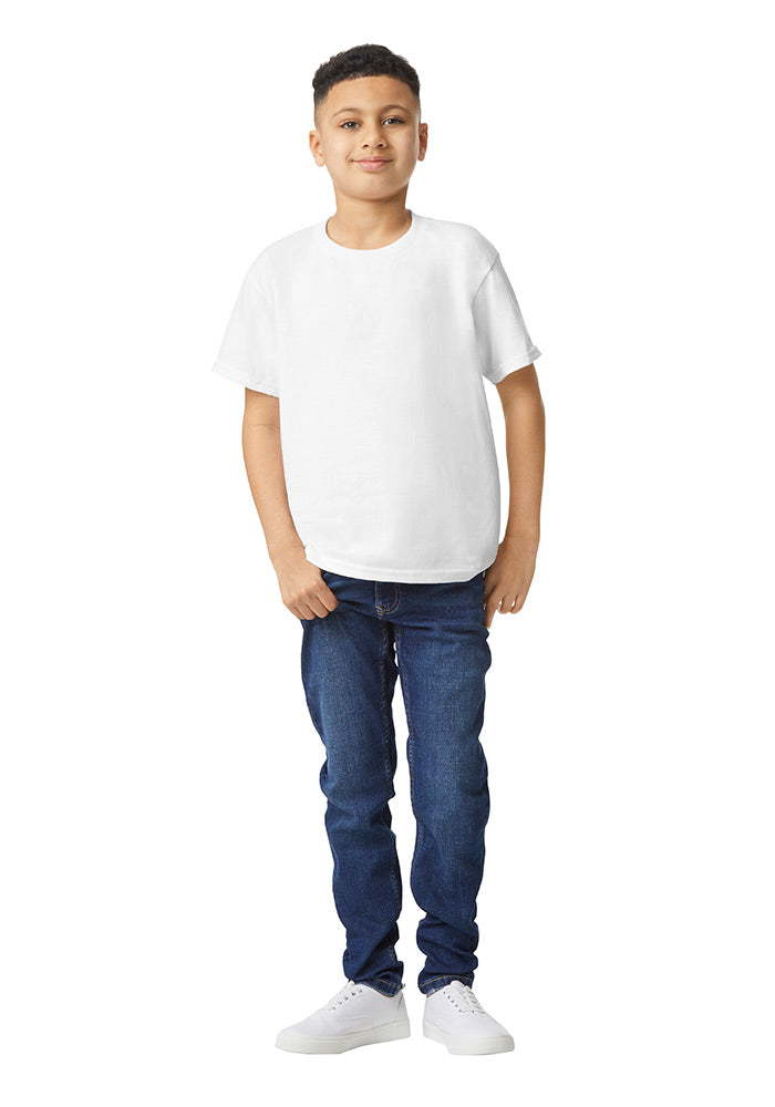 A boy wearing a Gildan 5.3 oz. heavy cotton, short-sleeved white t-shirt and blue jeans on a white background.