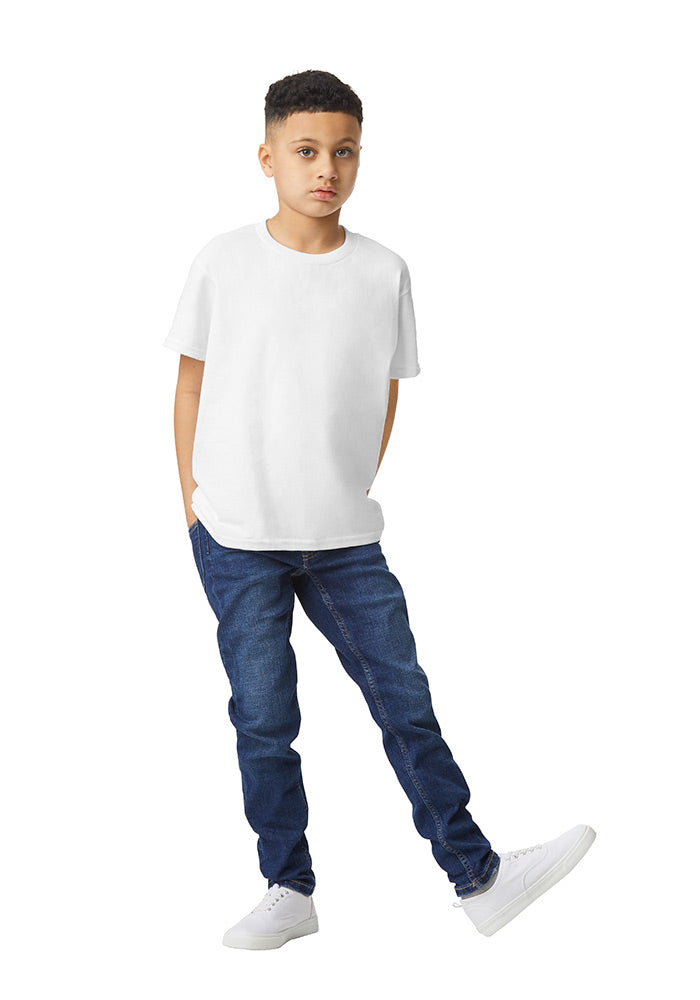 A boy wearing a Gildan 5.3 oz. heavy cotton, short-sleeved white t-shirt and blue jeans on a white background.