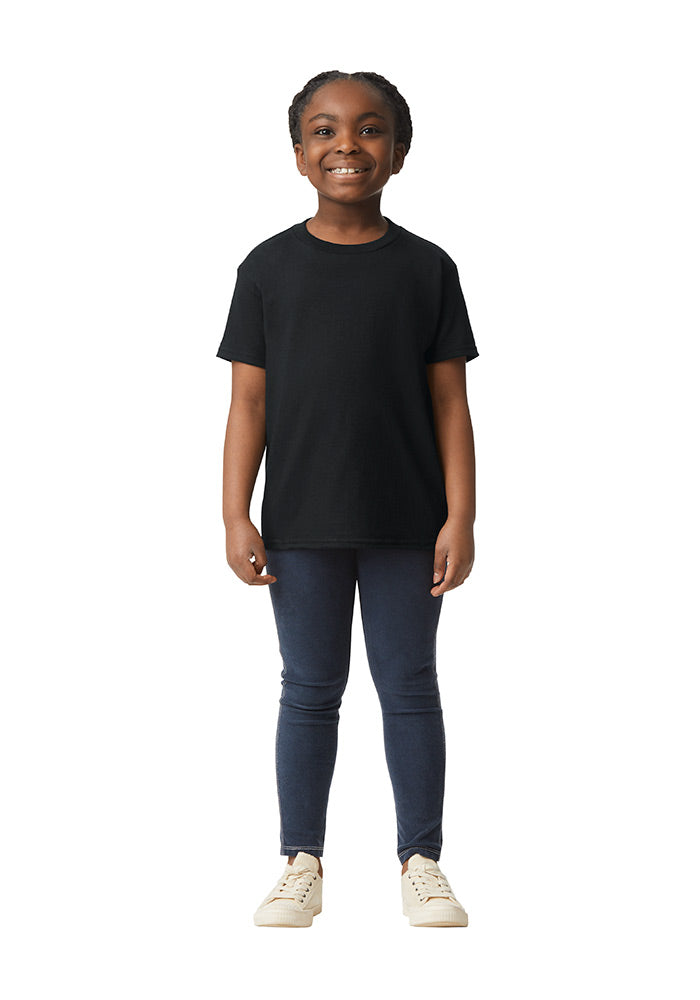 A girl wearing a Gildan 5.3 oz. heavy cotton, short-sleeved black t-shirt and blue jeans on a white background.