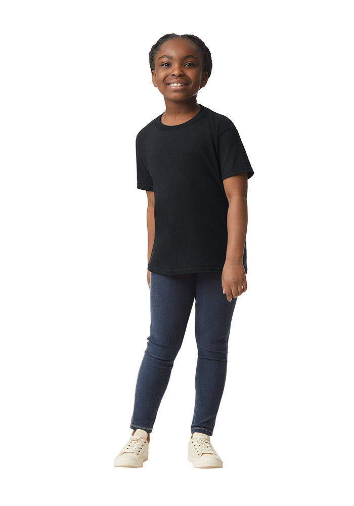 A child wearing a Gildan 5.3 oz. heavy cotton, short-sleeved black t-shirt and blue jeans on a white background.