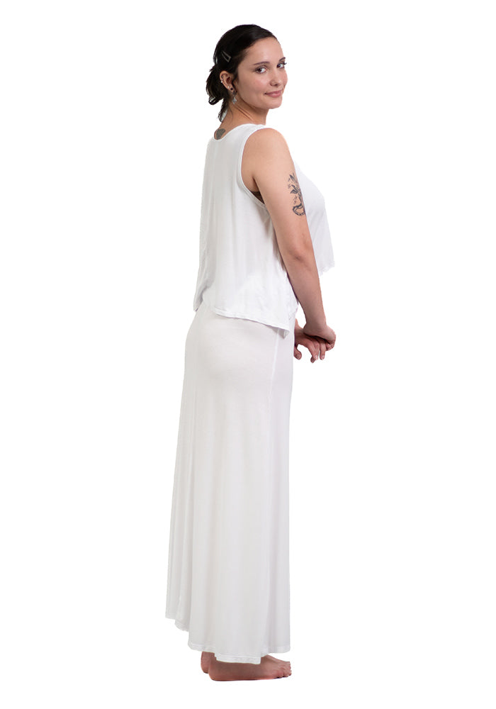 Woman wearing a white sleeveless hi lo top and white pants on a white background,